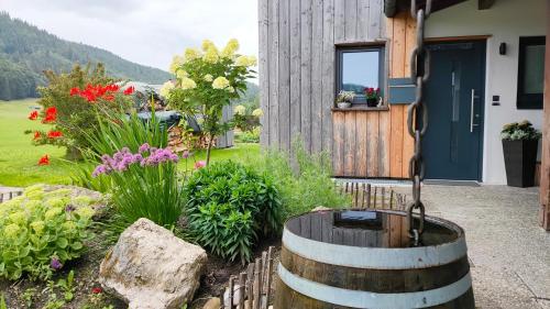a garden with a barrel and flowers in front of a house at Ferienwohnung Werner in Inzell
