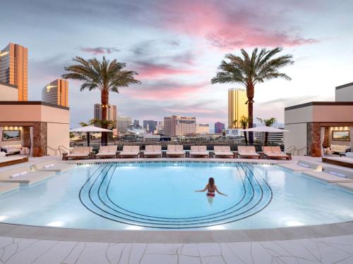 a woman swimming in a pool on top of a building at Conrad Las Vegas At Resorts World in Las Vegas