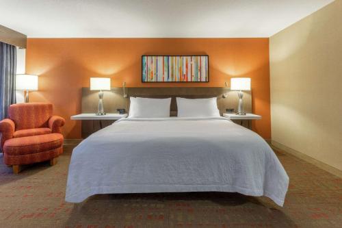 a bedroom with a large bed and a chair at Hilton Garden Inn Chicago/Tinley Park in Tinley Park