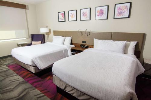 a hotel room with two beds with white sheets at Hilton Garden Inn Tampa Suncoast Parkway in Lutz