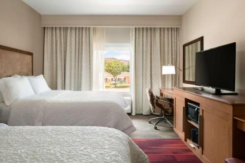 a hotel room with two beds and a flat screen tv at Hampton Inn Kanab in Kanab