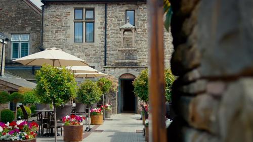 a building with an umbrella and tables and chairs at Lanelay Hall Hotel & Spa in Hensol
