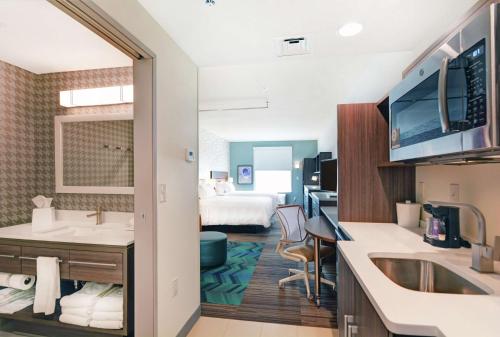 グランドジャンクショ​​ンにあるHome2 Suites By Hilton Grand Junction Northwestのバスルームとベッドルームが備わるホテルルームです。