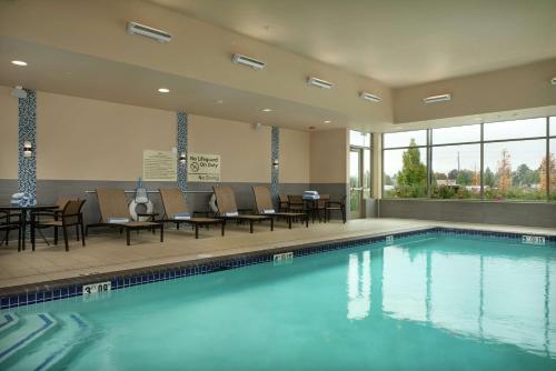 a swimming pool with chairs and tables in a building at Hampton Inn & Suites Portland/Vancouver in Vancouver