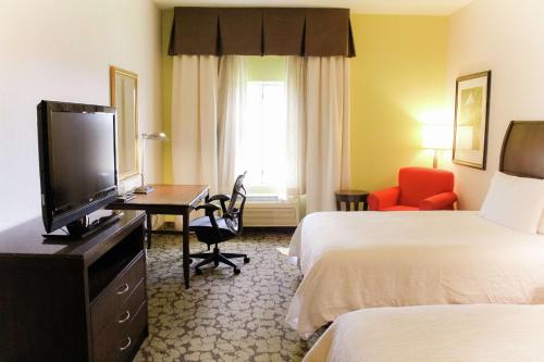 a hotel room with two beds and a flat screen tv at Hilton Garden Inn Redding in Redding