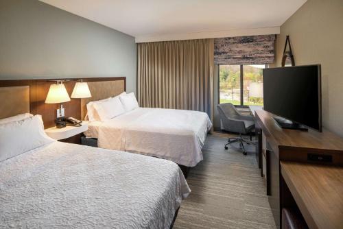 a hotel room with two beds and a flat screen tv at Hampton Inn & Suites Binghamton/Vestal in Vestal