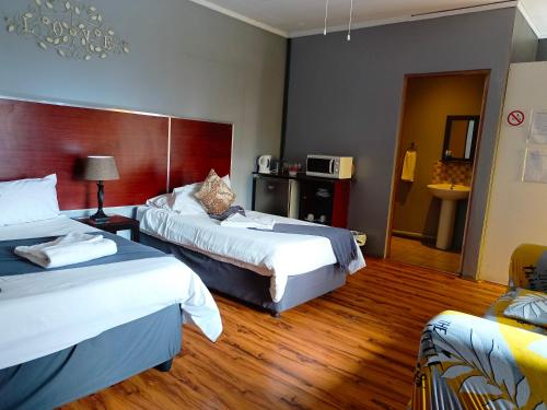 una habitación de hotel con 2 camas y una habitación con en 21 On Coetzee Guest House en Bloemfontein