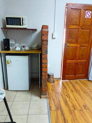 a kitchen with a table and a refrigerator and a door at 21 On Coetzee Guest House in Bloemfontein