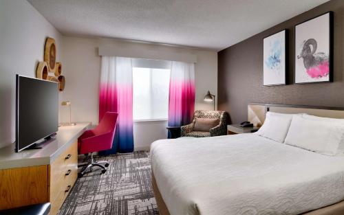 a hotel room with a bed and a flat screen tv at Hilton Garden Inn Bozeman in Bozeman