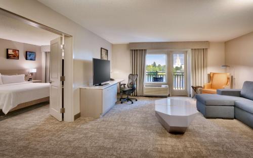 Cette chambre comprend un lit, un canapé et une télévision. dans l'établissement Hilton Garden Inn Idaho Falls, à Idaho Falls
