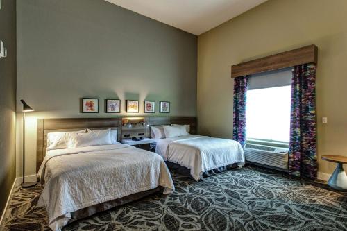 a hotel room with two beds and a window at Hilton Garden Inn Topeka in Topeka