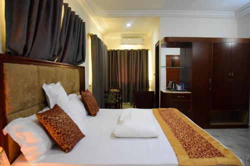ein Schlafzimmer mit einem großen weißen Bett mit braunen Kissen in der Unterkunft Dellagio Hotel in Wa