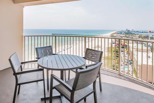 a table and chairs on a balcony with a view of the beach at Hilton Pensacola Beach in Pensacola Beach