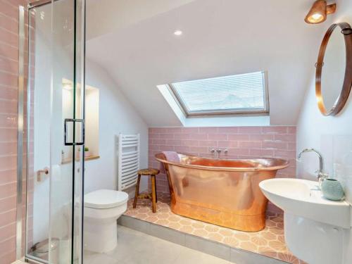 a bathroom with a copper tub and a toilet and a sink at Luxury sea-view apartment in Tenby - Floral Corner in Pembrokeshire