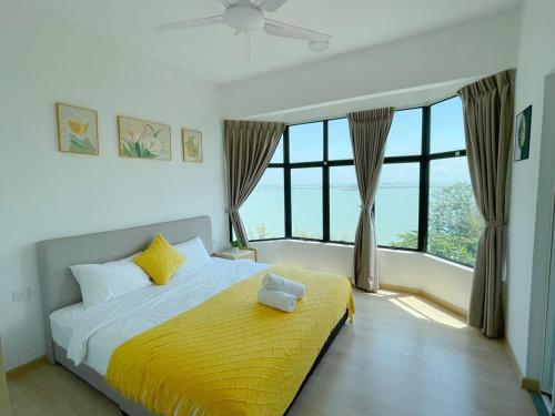 a bedroom with a bed with yellow sheets and windows at Mutiara Melaka Beach Resort by Minso in Tangga Batu
