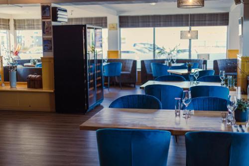 a restaurant with blue chairs and wooden tables and tablesktop at Hotel de Boegschroef in Delfzijl