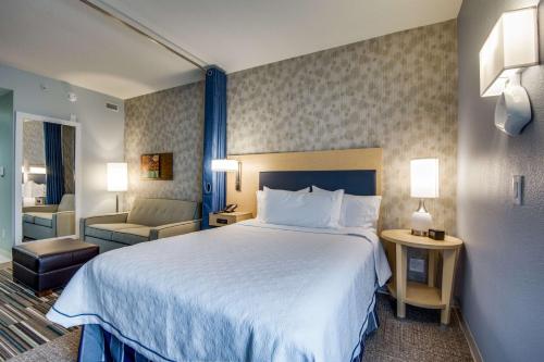 a hotel room with a large bed and a chair at Home2 Suites by Hilton DFW Airport South Irving in Irving