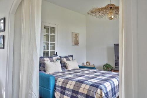 een slaapkamer met een blauw bed en een geruite deken bij Maison cosy proche de la mer in Binic