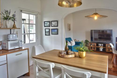 a kitchen with a wooden table and white chairs at Maison cosy proche de la mer in Binic-Etables-sur-Mer