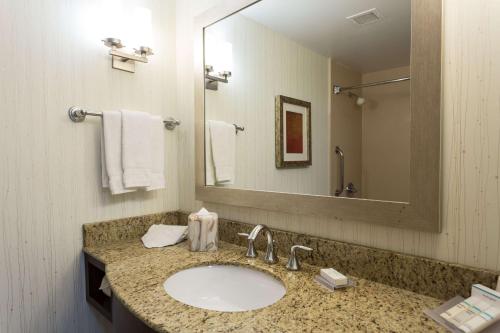a bathroom with a sink and a mirror and towels at Hilton Garden Inn San Mateo in San Mateo