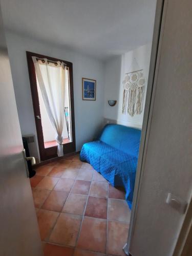 um quarto com uma cama azul e uma janela em Appartement aux Stes Maries de la Mer em Saintes-Maries-de-la-Mer