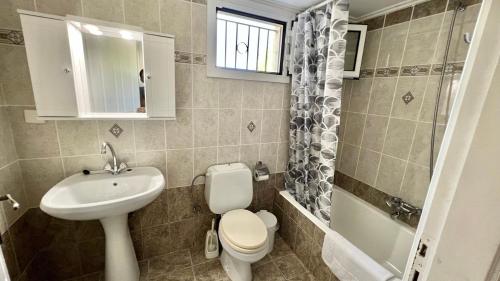 uma casa de banho com um lavatório, um WC e um lavatório. em Villa Evgenia em Yénion