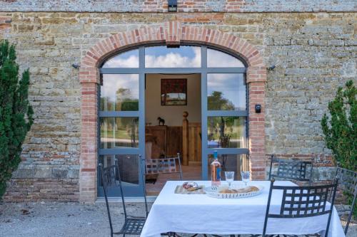 a table in front of a brick building with an open door at Le Domaine de Ravenoville - Pierres d'Histoire in Ravenoville