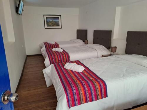a group of three beds in a room at Marina's House Cusco Centro in Cusco