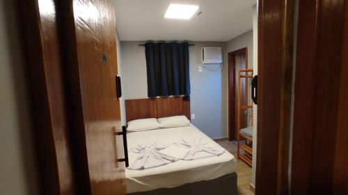 a small bedroom with a bed with white sheets at Hotel Platina in Juiz de Fora