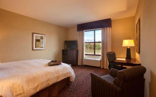 um quarto de hotel com uma cama e uma cadeira e uma janela em Hampton Inn Marquette-Waterfront em Marquette