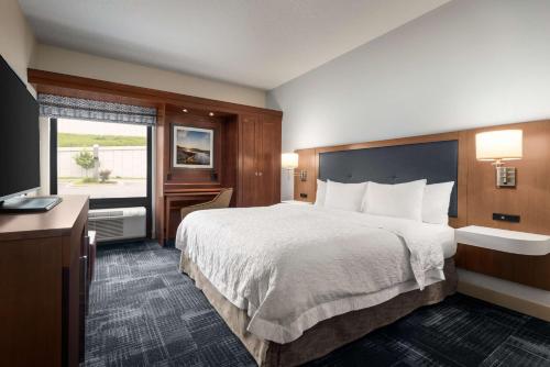 um quarto de hotel com uma cama grande e uma televisão em Hampton Inn Wausau em Wausau