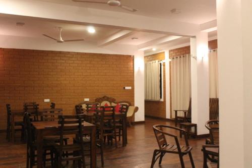 a dining room with tables and chairs and a brick wall at Windy Hanthana in Kandy
