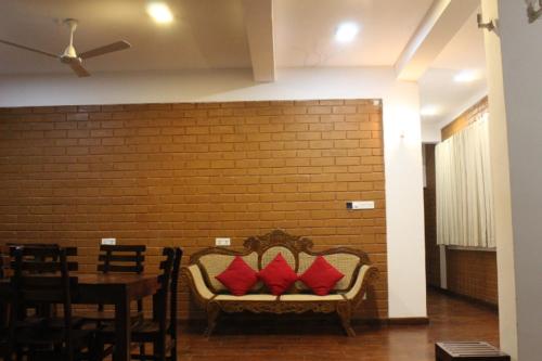 a couch with two red pillows on it next to a brick wall at Windy Hanthana in Kandy