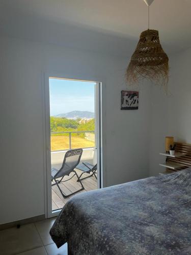 - une chambre avec un lit et un balcon avec une chaise dans l'établissement La Lond'ella - Appt à 1,5km de la mer à Porticcio, à Grosseto-Prugna