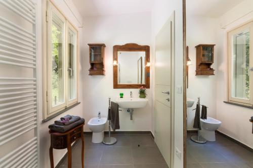 bagno con 2 servizi igienici, lavandino e specchio di Casa Sul Serra a Calci