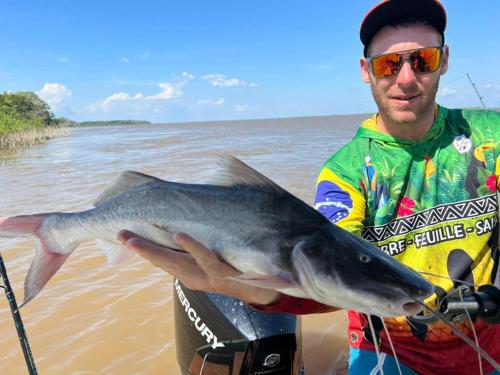 a man holding a fish in his hand at River X House in Manaus