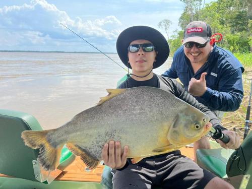 two people on a boat with a large fish at River X House in Manaus