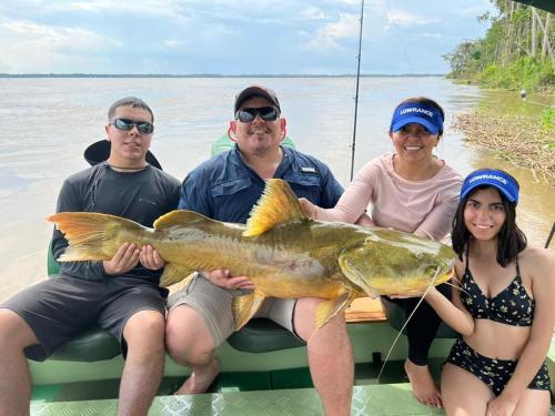 a group of people on a boat with a large fish at River X House in Manaus