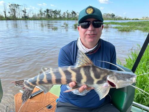 a man holding a large fish in a boat at River X House in Manaus