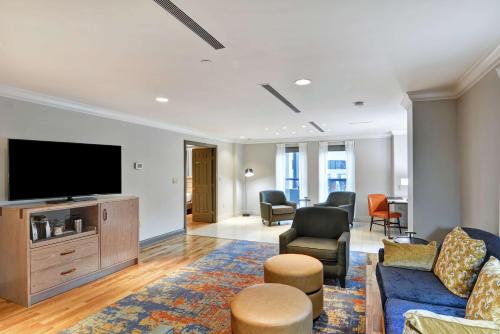 a living room with a tv and a couch and chairs at The Cincinnatian Curio Collection by Hilton in Cincinnati