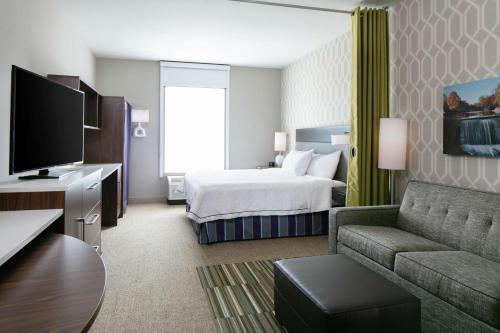 a hotel room with a bed and a couch at Home2 Suites By Hilton Menomonee Falls Milwaukee in Menomonee Falls