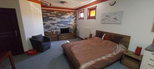 a bedroom with a bed and a chair and a television at Apartment v historickom centre in Bardejov