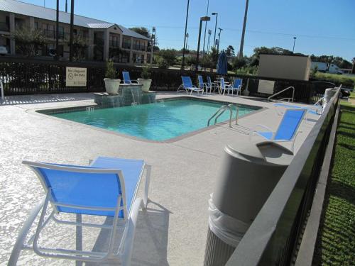 a swimming pool with blue chairs and a trash can at Hampton Inn Lindale/Tyler in Lindale