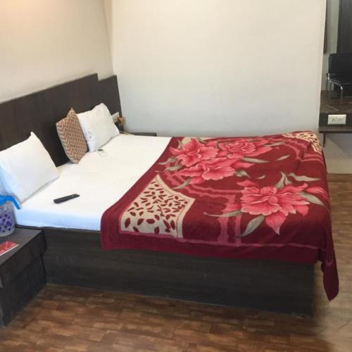 a bedroom with a bed with a red blanket on it at Hotel Long Stay in Ahmedabad