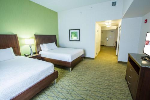 a hotel room with two beds and a hallway at Hilton Garden Inn State College in State College