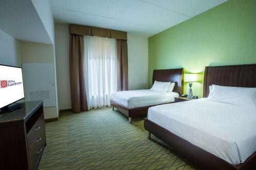 a hotel room with two beds and a flat screen tv at Hilton Garden Inn State College in State College