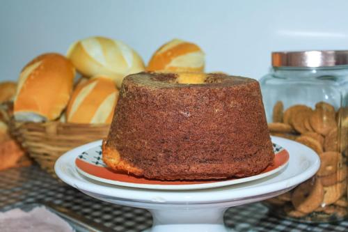a cake on a plate next to a basket of bread at Pousada BR101 in Angra dos Reis
