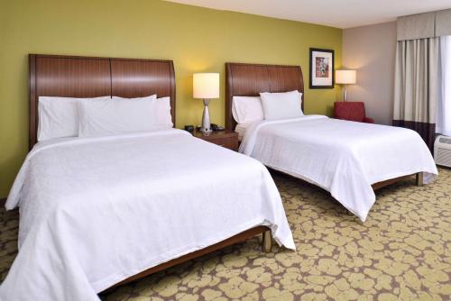 カーメルにあるHilton Garden Inn Indianapolis/Carmelの白いシーツが敷かれたホテルの部屋にベッドが2つある