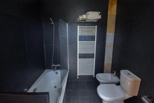 a bathroom with a toilet and a tub and a sink at Casa do Pinto in Arouca