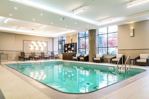 uma piscina no átrio do hotel com cadeiras e mesas em DoubleTree by Hilton Kitchener em Kitchener